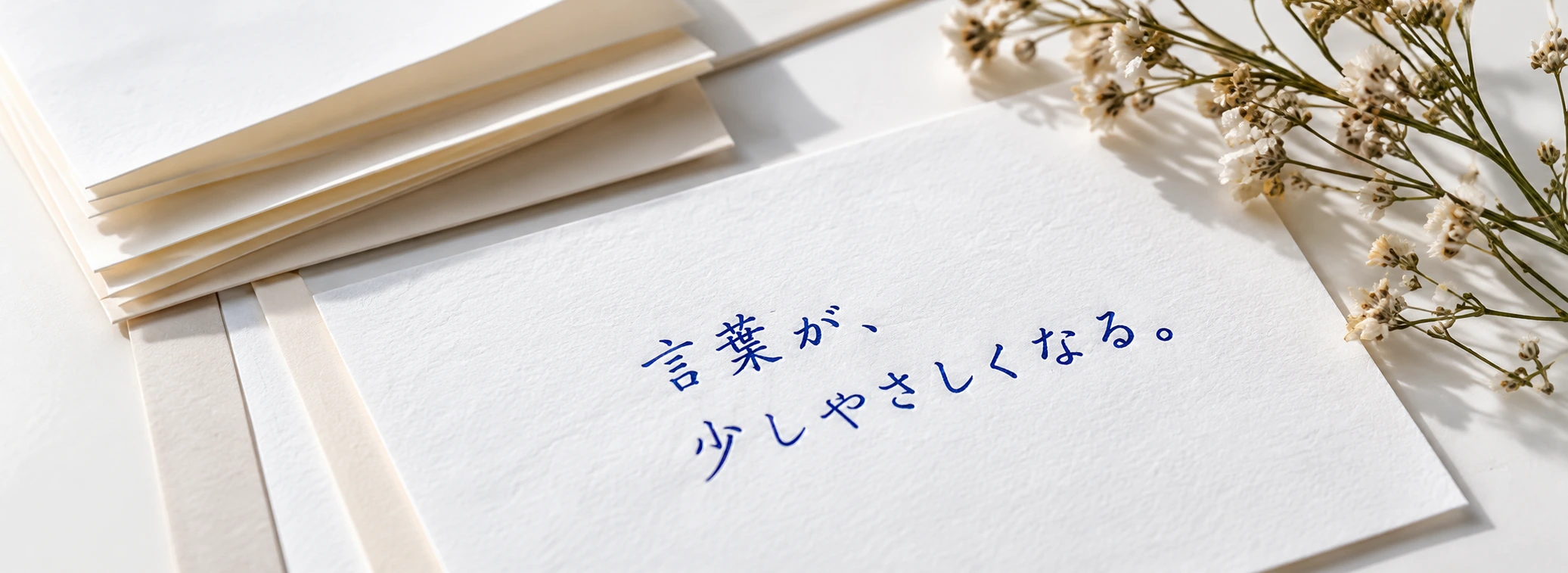 万年筆で「言葉が、少しやさしくなる。」と書かれた便箋と、かすみ草